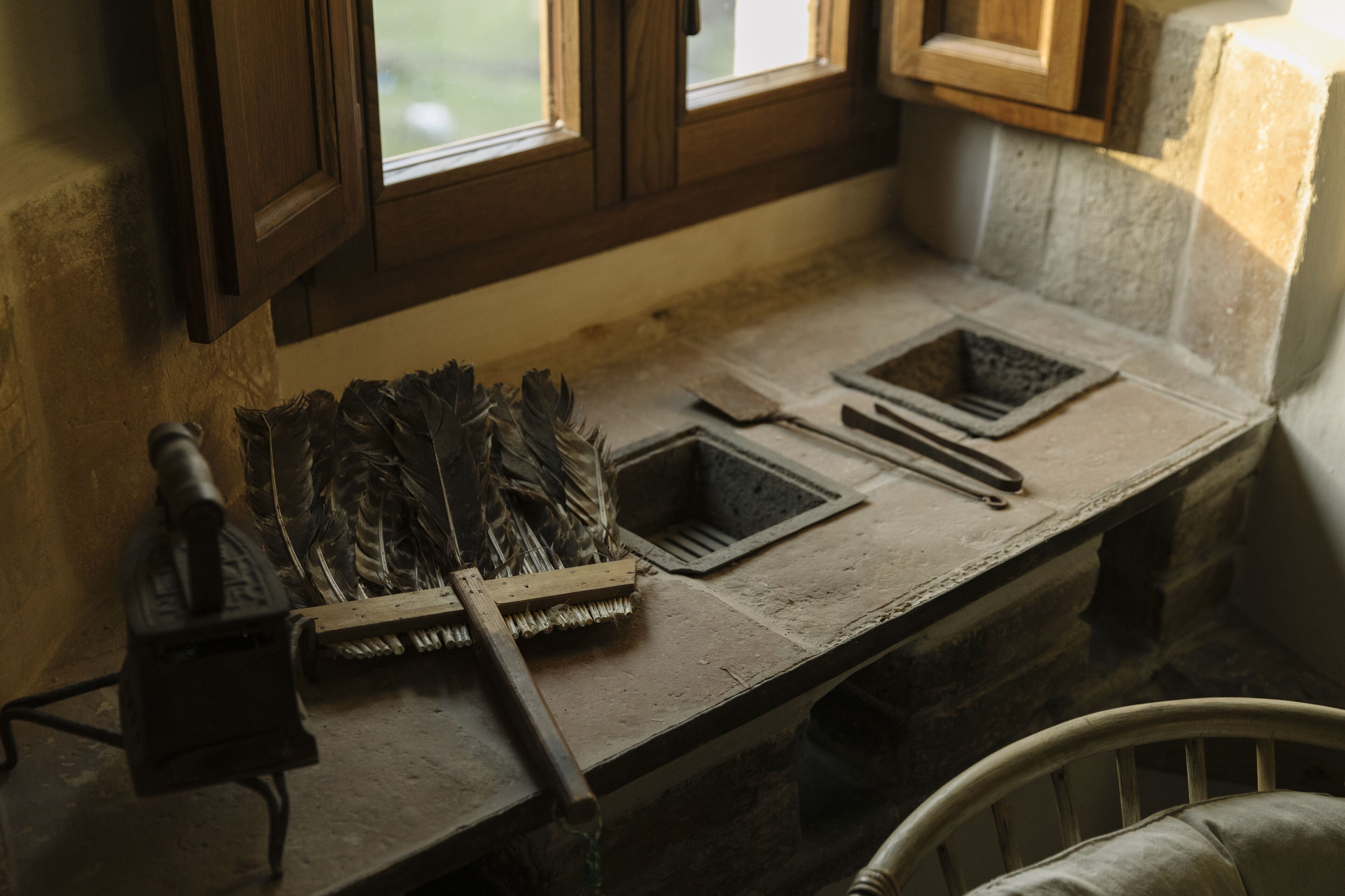 Une cuisine rustique avec un plan de travail en pierre, des armoires en bois et une fenêtre donnant sur un paysage verdoyant.