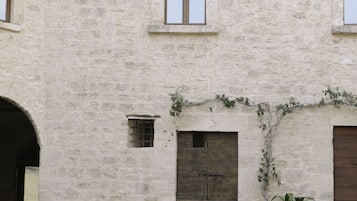 A stone building with multiple windows and doors, potted plants, and a courtyard.