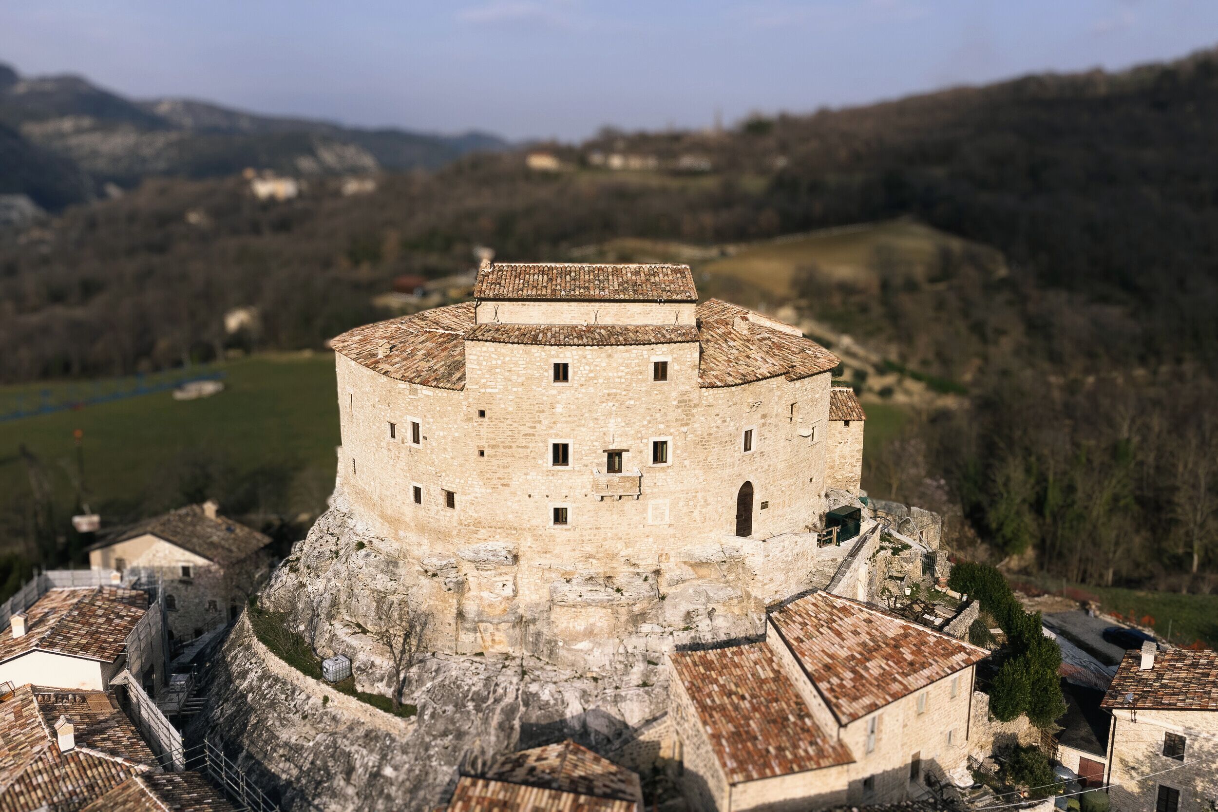 Un castillo de piedra histórico con una torre redonda, rodeado por un foso y edificios adyacentes.