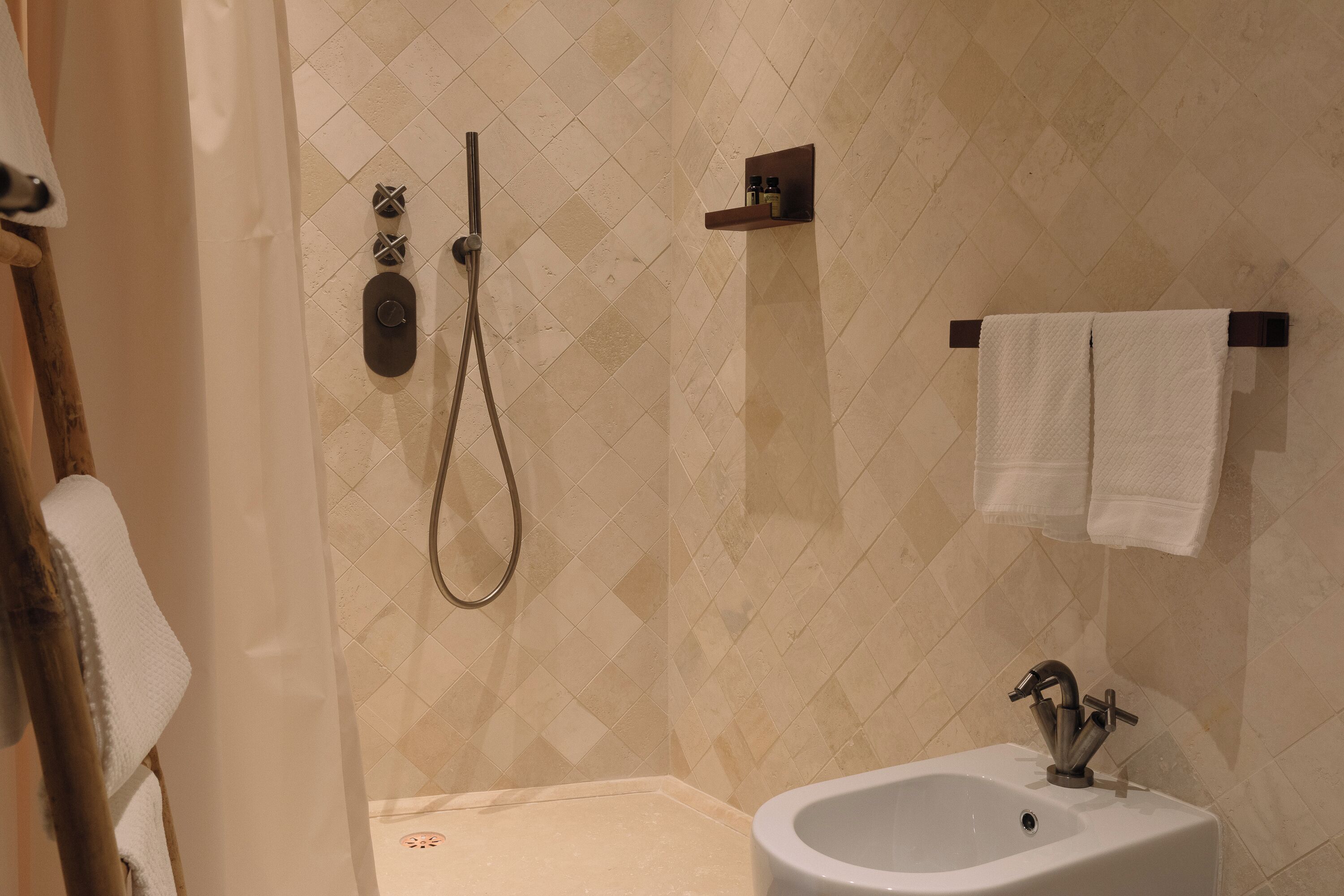 A bathroom with a shower, a sink, and a towel rack.