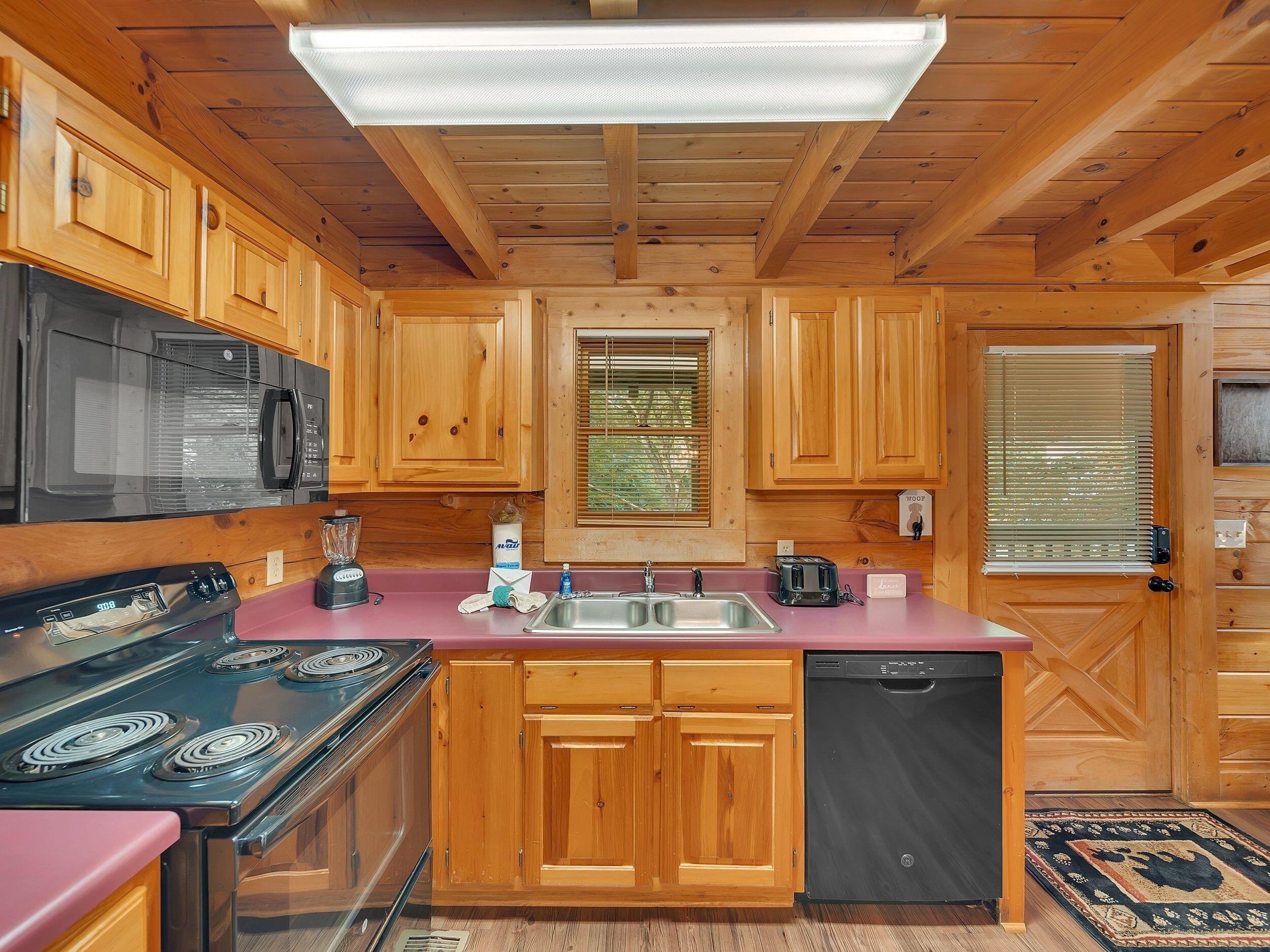 Une cuisine avec des meubles de rangement en bois, une cuisinière noire, un évier et un lave-vaisselle.