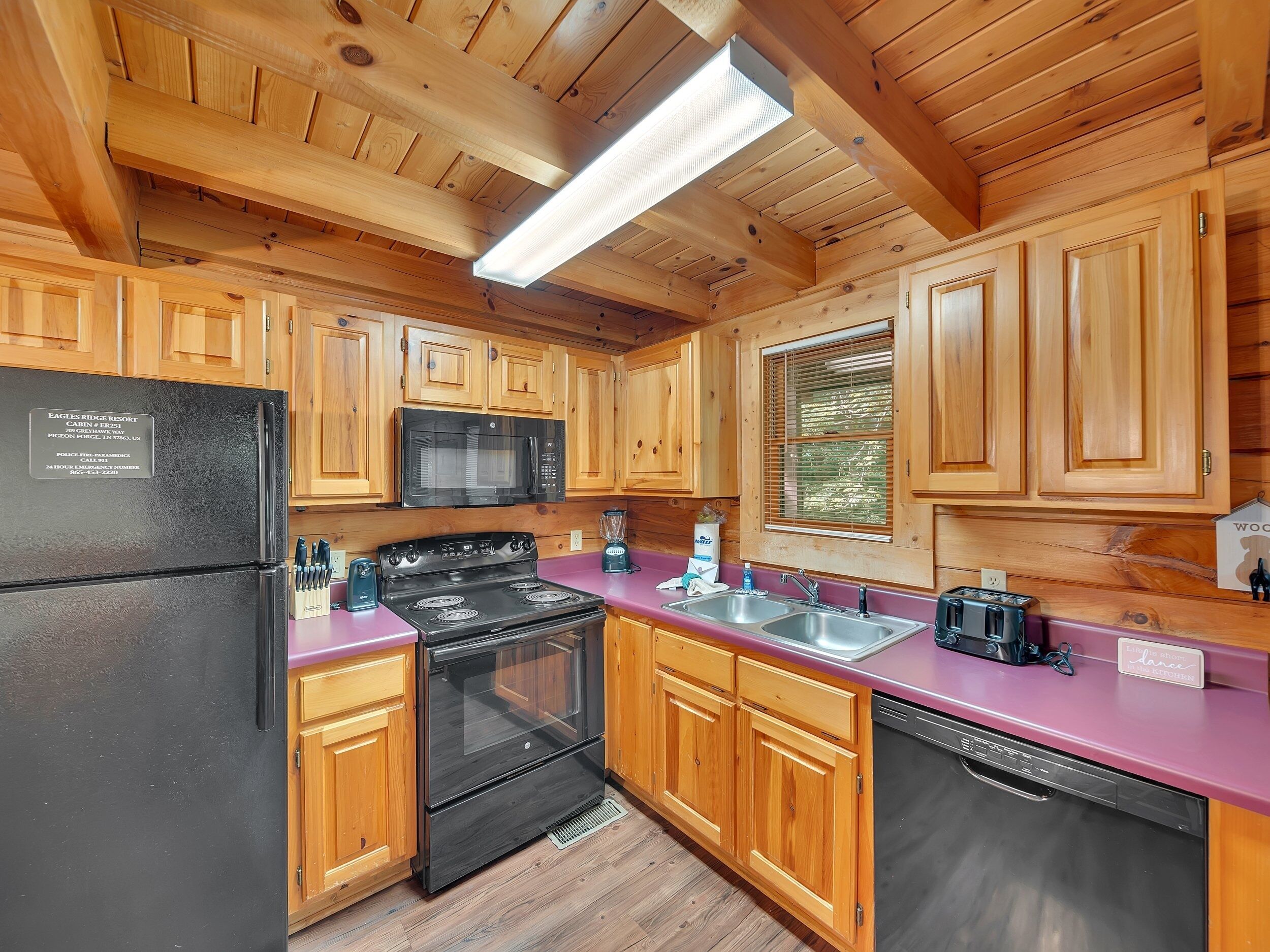 A kitchen with wooden cabinets, a black refrigerator, a microwave, a stove, and a dishwasher.