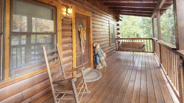 A wooden cabin with a porch, a rocking chair, and a decorative scarecrow. - Er91 - Eagle's Beauty - Great Location - Close To All The Action! 2 Bedroom Cabin by RedAwning (Pigeon Forge)