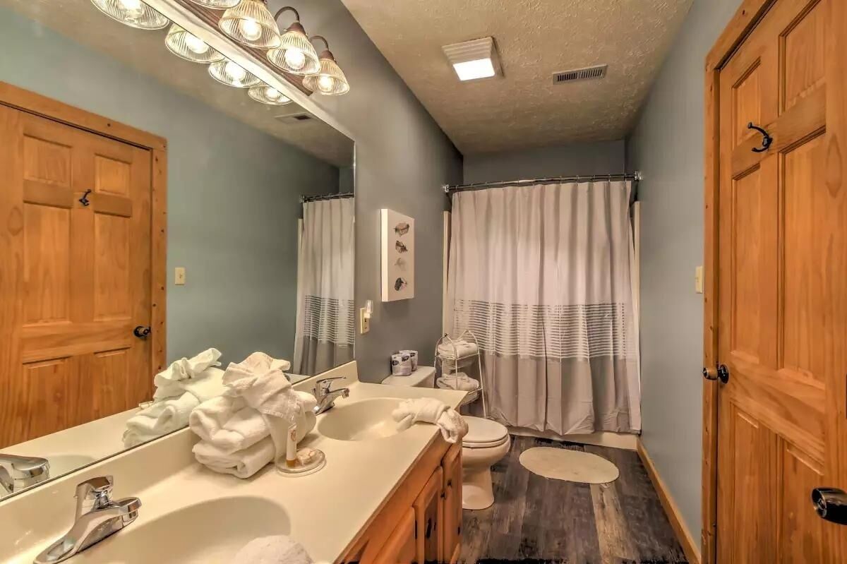 A bathroom with a vanity, sink, mirror, and toilet.