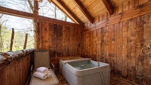 A wooden cabin with a sauna, a cushioned chair, and a wooden floor.