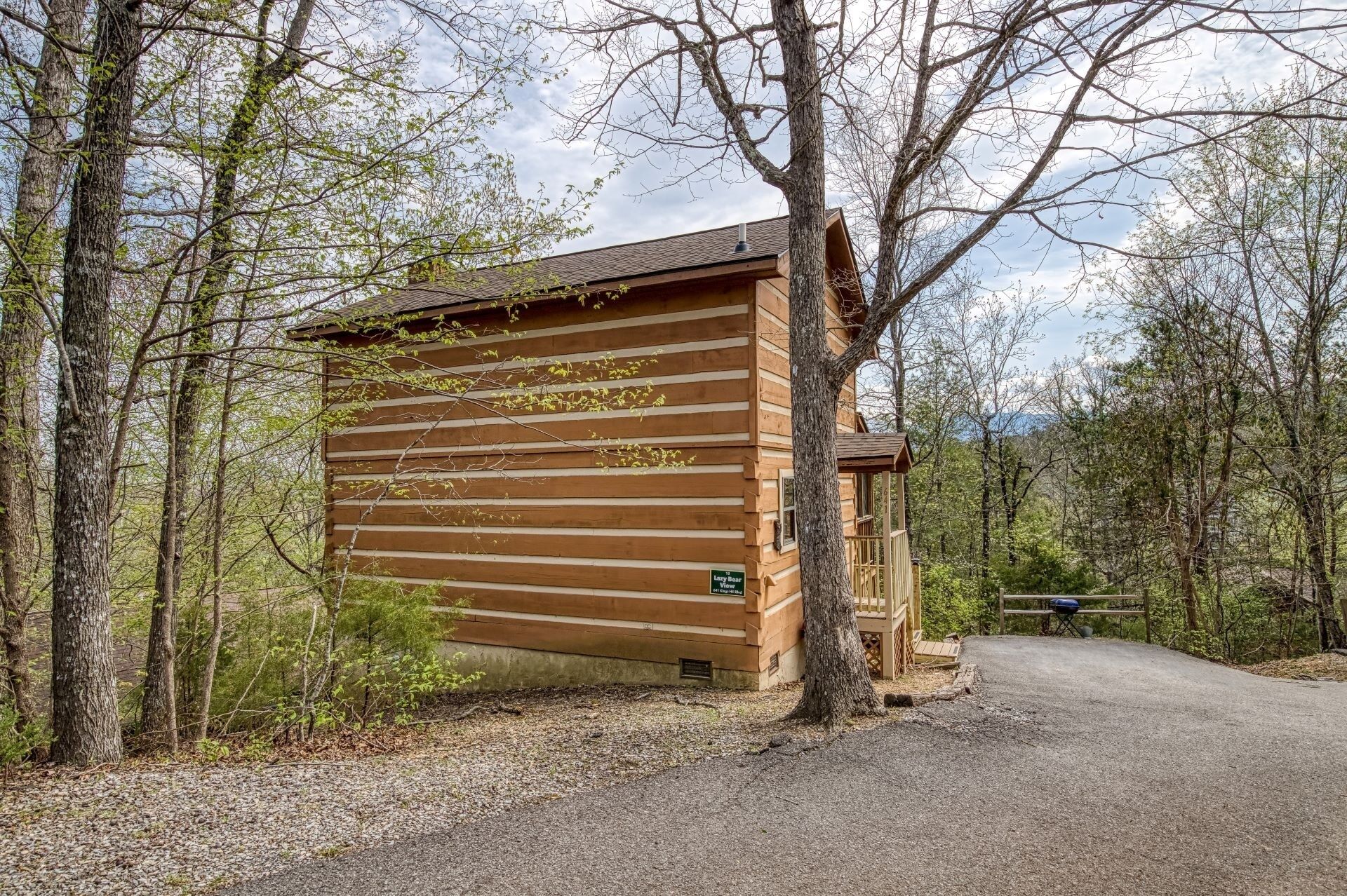 Eine Blockhütte mit einem Schotterweg und Blick auf den umliegenden Wald.