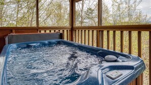 A hot tub on a wooden deck with a view of trees.