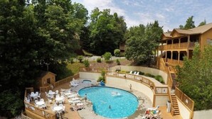 A wooden cabin with a pool and outdoor seating.