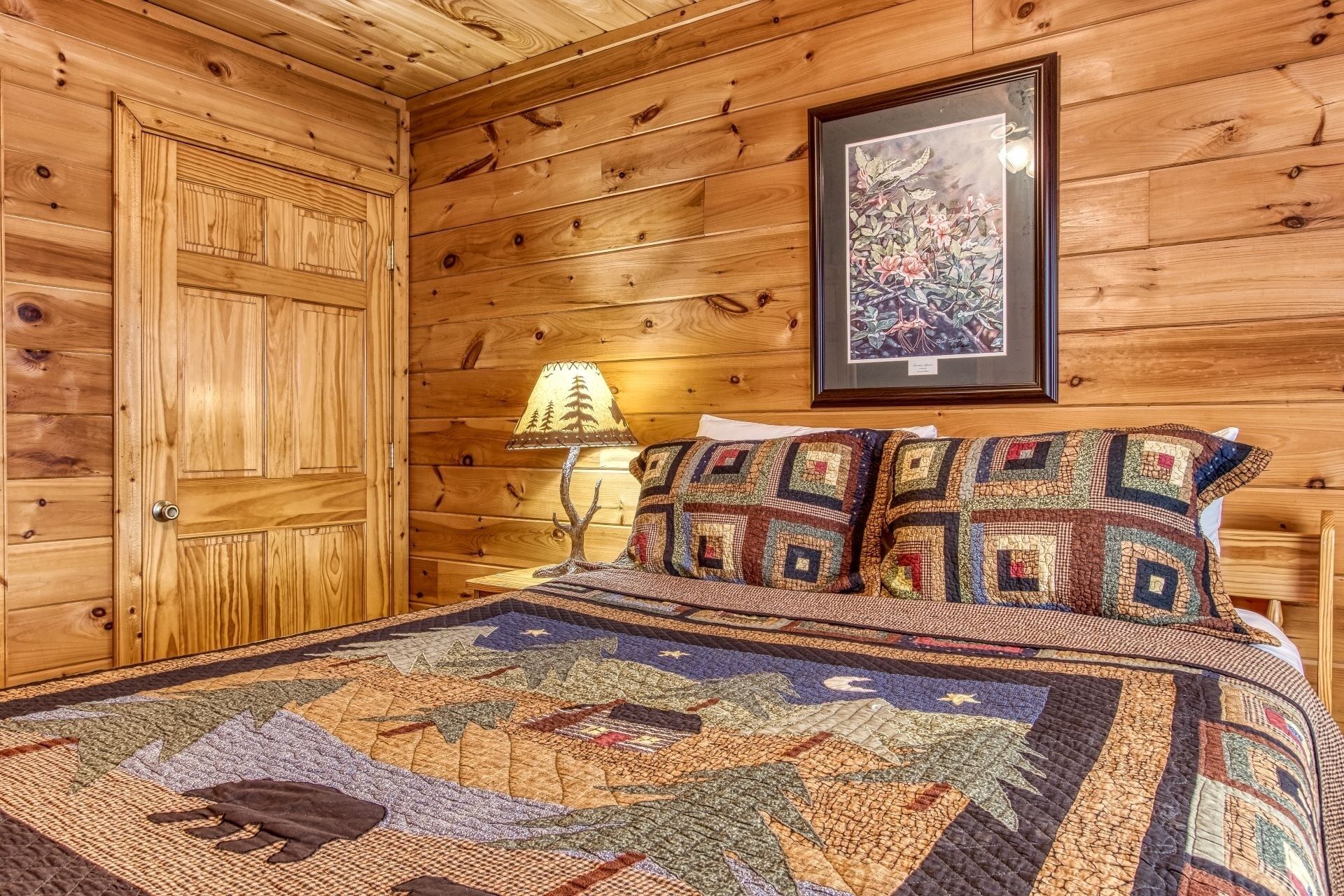 Una habitación de cabaña de madera con una cama, un cuadro en la pared y una lámpara.