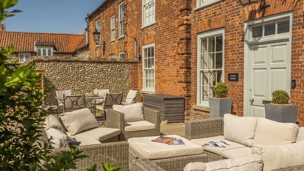 A brick building with a stone wall, outdoor wicker furniture, and a sign reading "Alice House". - Alice House, Burnham Market, Norfolk (Burnham Market)