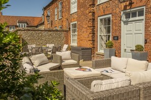 A brick building with a stone wall, outdoor wicker furniture, and a sign reading "Alice House". - Alice House, Burnham Market, Norfolk (Burnham Market)