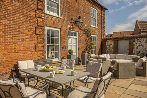 A patio with a table set for two, outdoor seating, and a brick building with a white door labeled "Alice House". - Alice House, Burnham Market, Norfolk (Burnham Market)