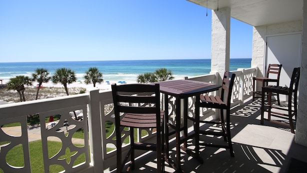 A balcony with a table and chairs overlooking a beach. - 448 El Matador 2 Bedroom Condo by RedAwning (Fort Walton Beach)