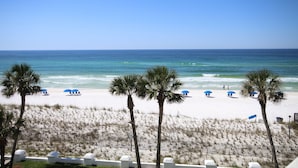 A beach with palm trees, umbrellas, and a fence. - 448 El Matador 2 Bedroom Condo by RedAwning (Fort Walton Beach)