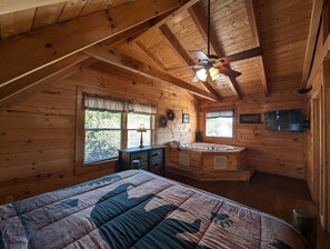 A cozy cabin bedroom with a bed, a vanity, a window, and a ceiling fan. - Ern807 - Black Bearry Ridge - Great Location! Close To All The Action! 6 Bedroom Cabin by RedAwning (Sevierville)