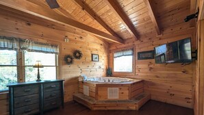 A wooden cabin interior with a wooden floor, a wooden dresser, a wooden bathtub, and a television mounted on the wall. - Ern807 - Black Bearry Ridge - Great Location! Close To All The Action! 6 Bedroom Cabin by RedAwning (Sevierville)