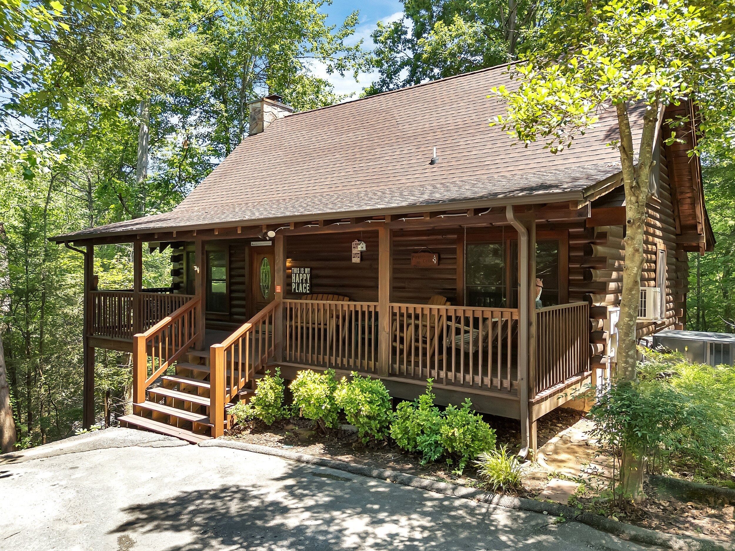 A log cabin with a porch, a staircase, and a sign that says "This is my happy place."