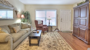 A living room with a sofa, armchair, coffee table, and a cabinet. - Colonial Crest 107 - Great Location! - You Can Walk To Town! 1 Bedroom Condo by RedAwning (Pigeon Forge)