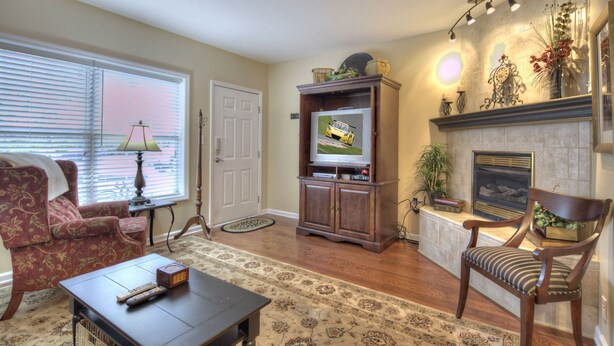A living room with a television, fireplace, and a red armchair. - Colonial Crest 107 - Great Location! - You Can Walk To Town! 1 Bedroom Condo by RedAwning (Pigeon Forge)