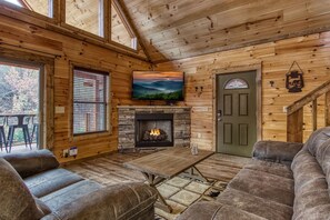 Een gezellig cabin interieur met een stenen open haard, houten wanden, een televisie en een groene deur.