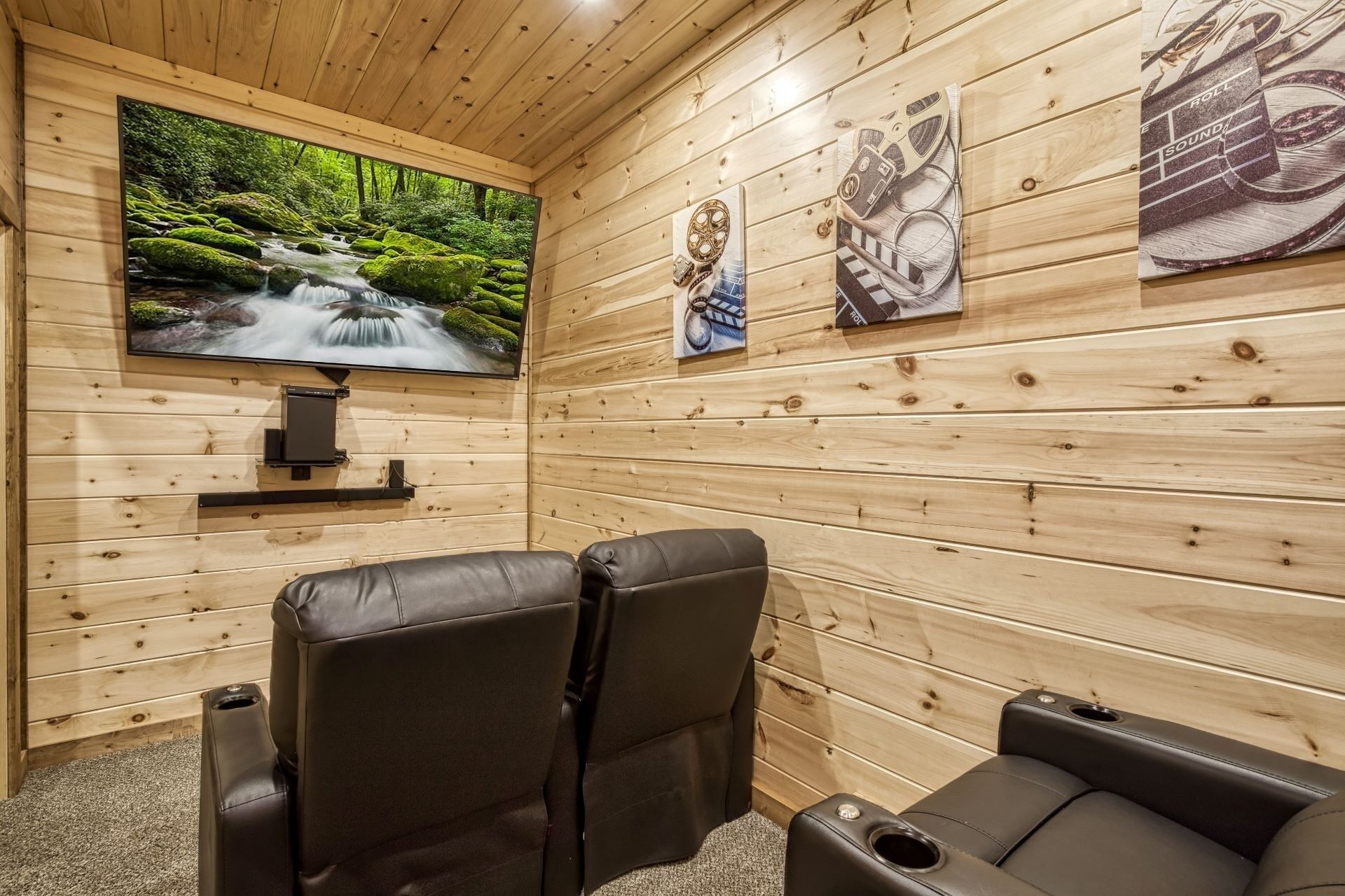 Uma sala de sauna com paredes de madeira, uma televisão na parede e duas cadeiras reclináveis.