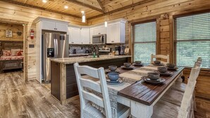 A rustic cabin interior with a kitchen, dining area, and a cozy sleeping area. - Ern841 - Sweet Feet Retreat - Location, Location, And Private Indoor Pool! 2 Bedroom Cabin by RedAwning (Pigeon Forge)