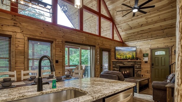 A cabin interior with a kitchen, dining area, and fireplace. - Ern841 - Sweet Feet Retreat - Location, Location, And Private Indoor Pool! 2 Bedroom Cabin by RedAwning (Pigeon Forge)