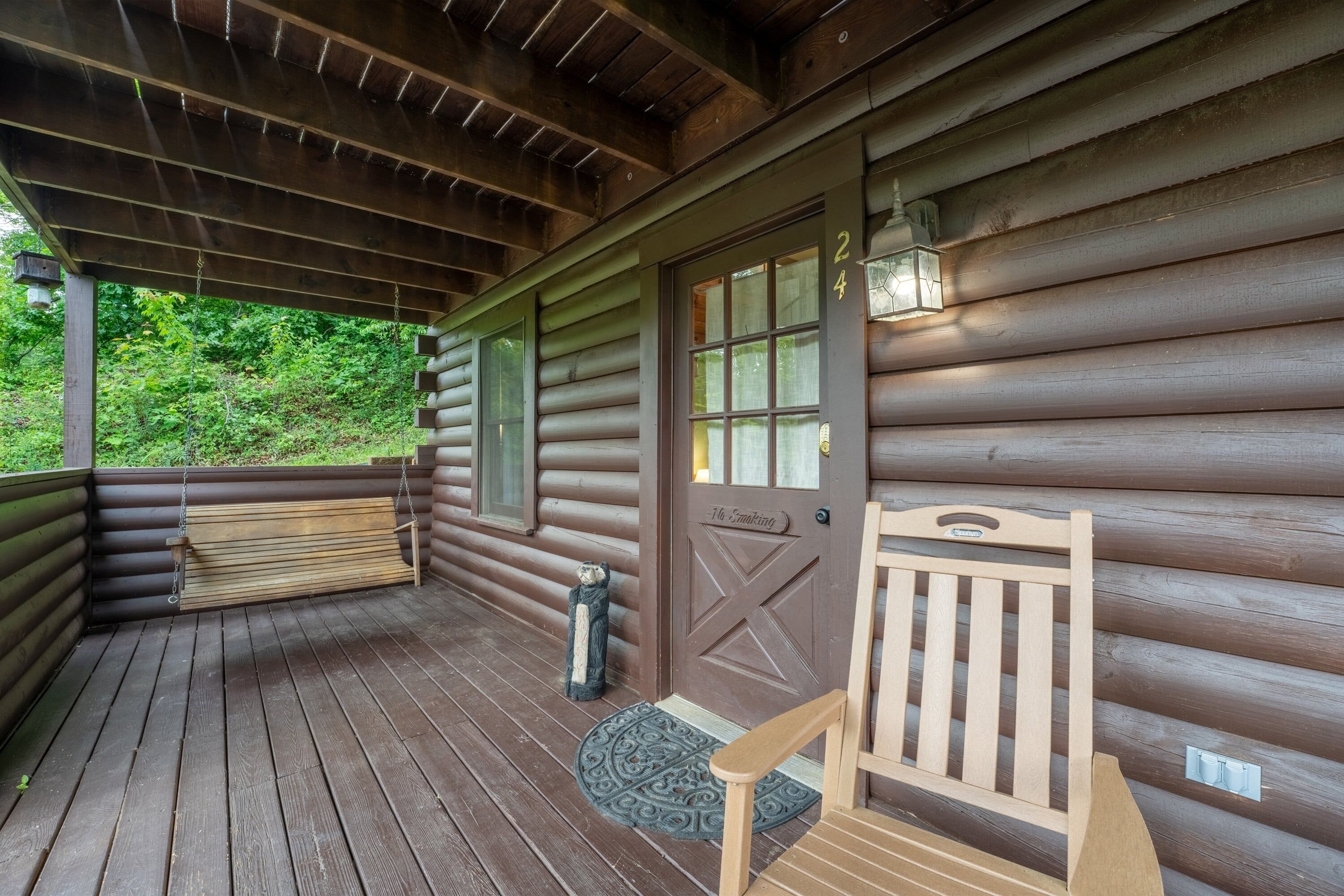 Eine Holzhütte mit Veranda, einer Bank, einer Tür und einer Laterne.