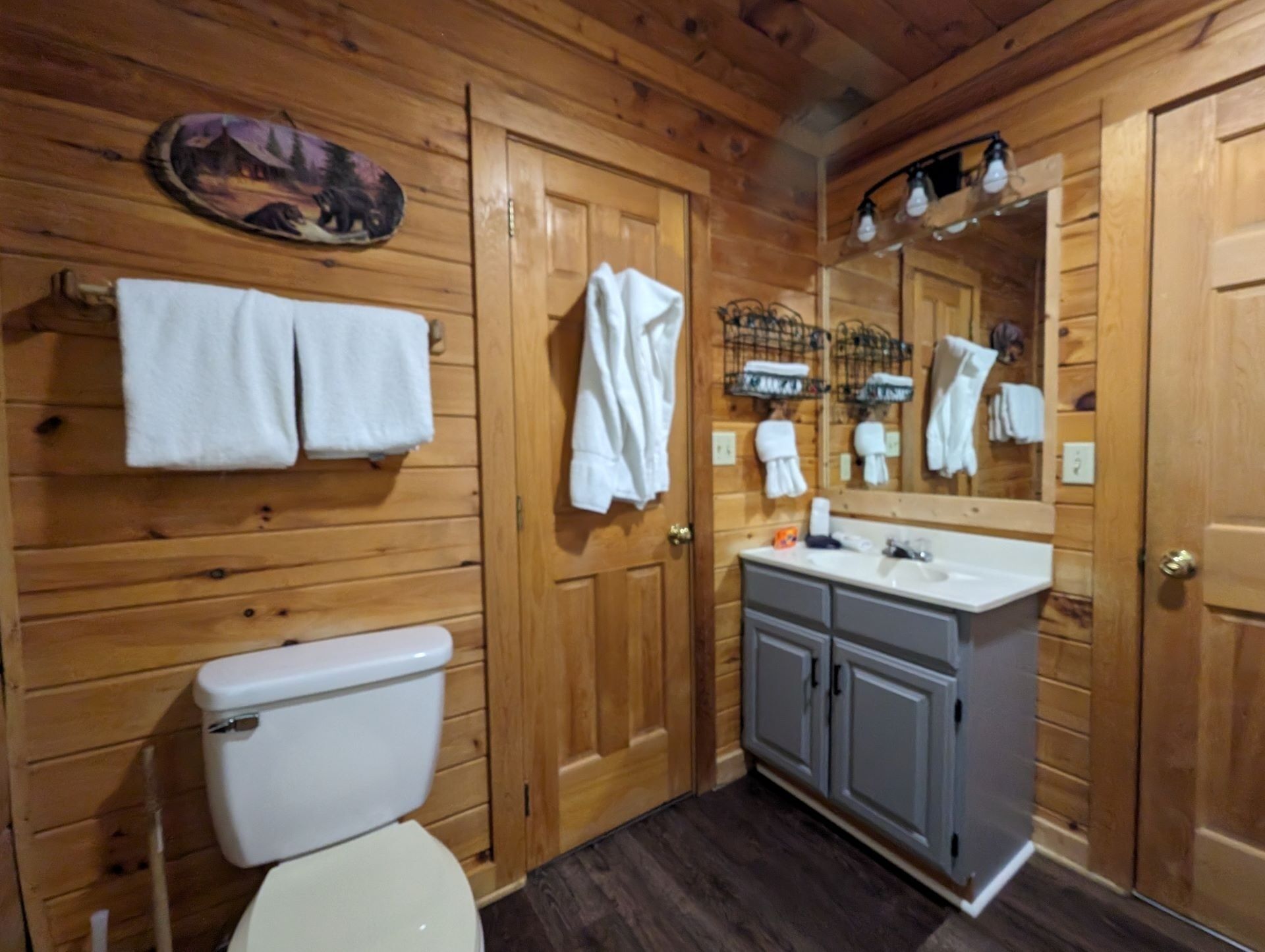 Un baño con paneles de madera, un inodoro, un lavabo y un espejo.