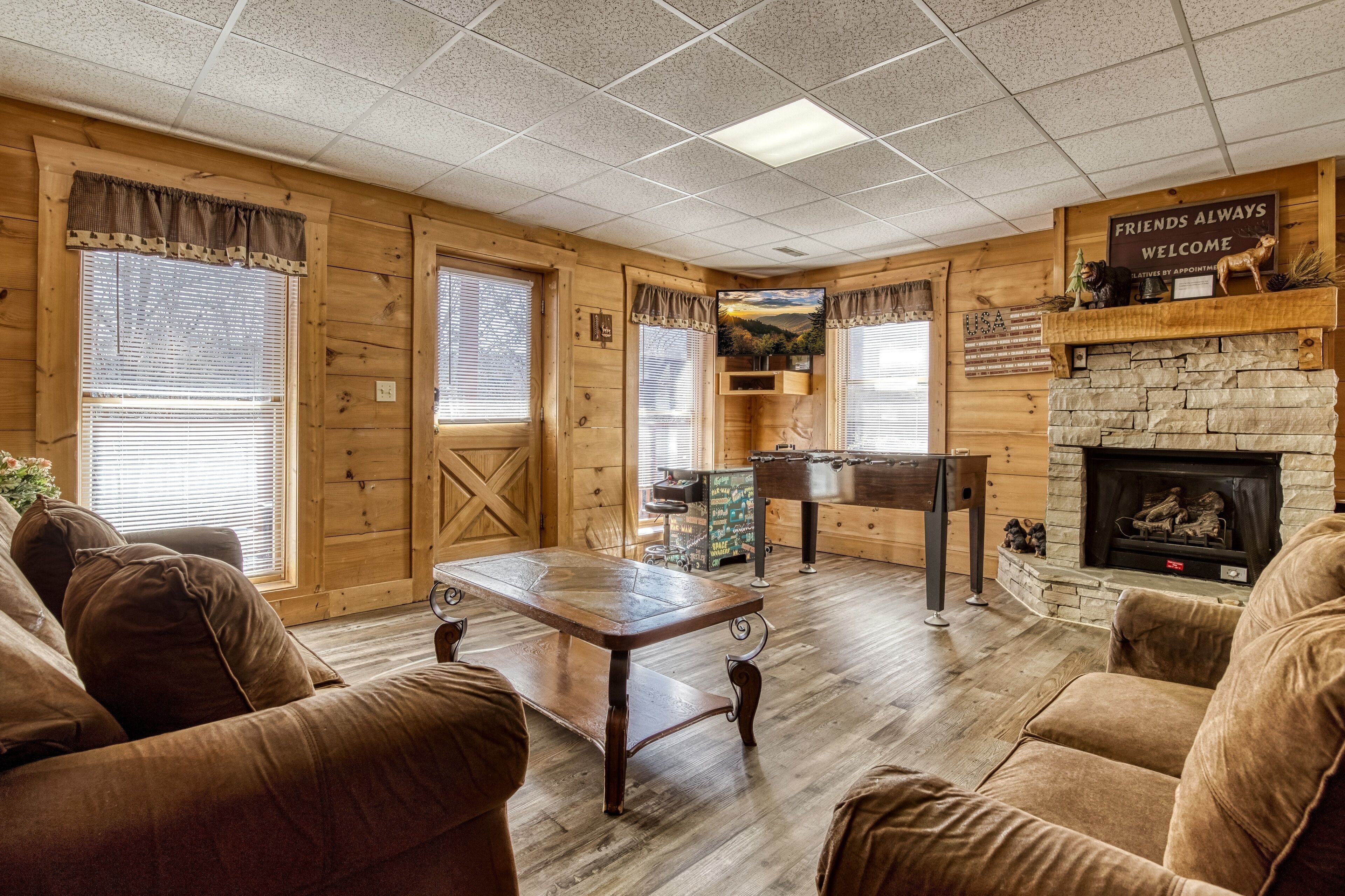 A cozy log cabin interior with wooden walls, a stone fireplace, and comfortable leather sofas.