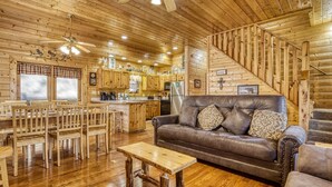 A wooden interior with a dining area, a sofa, and a staircase. - Er305- Bear Right Inn- Great Location- Close To Town 9 Bedroom Cabin by RedAwning (Pigeon Forge)
