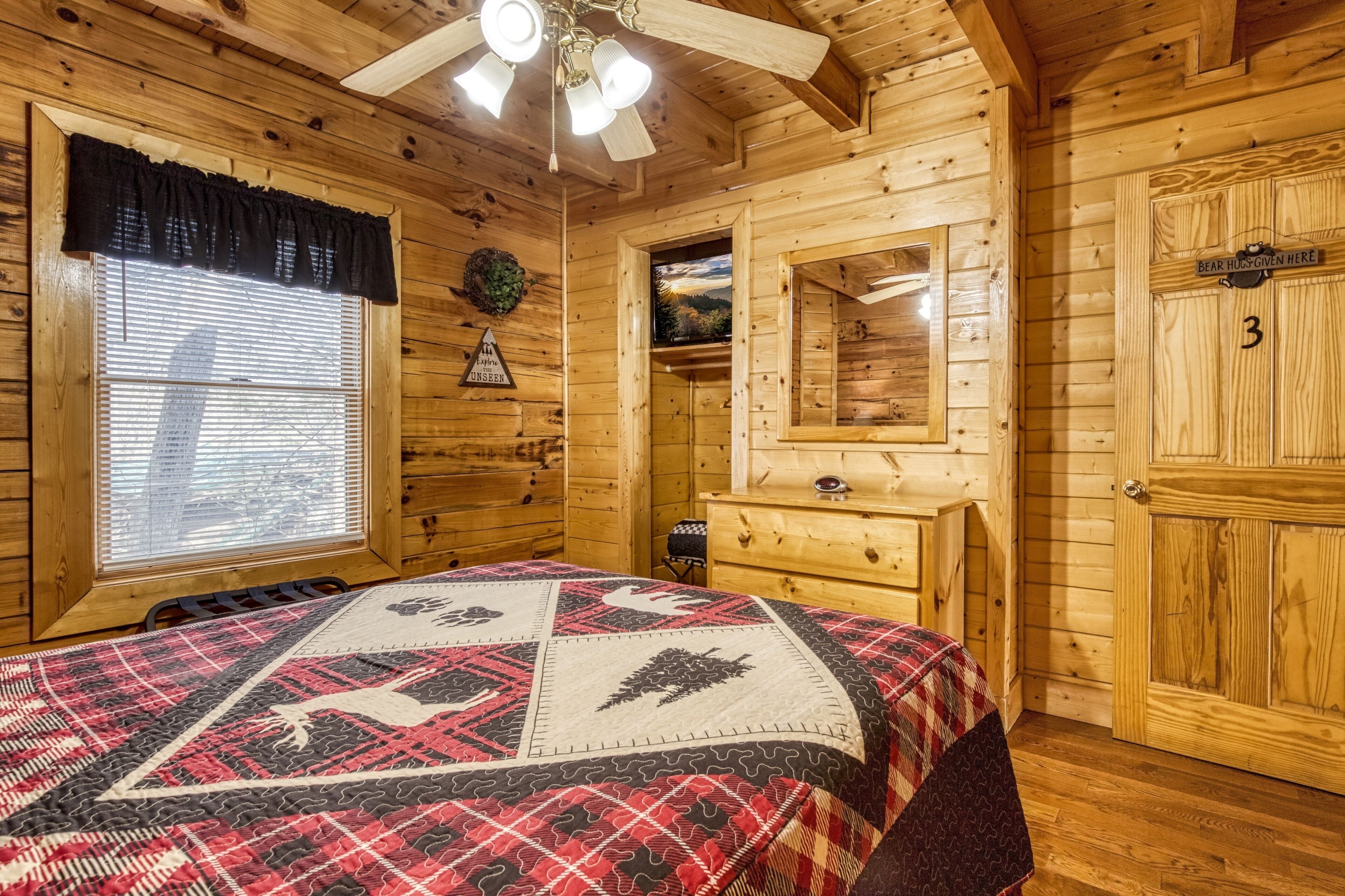 Une chambre dans une cabane en bois, avec un lit, une commode et un miroir.
