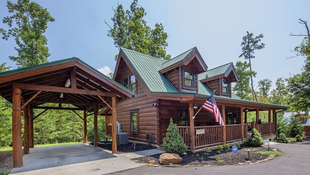 A log cabin with a covered porch, a flag, and a sign indicating a retreat. - Liam's Retreat - 2 Bedroom with GameRoom just minutes away from Pigeon Forge 2 Cabin by RedAwning (Sevierville)