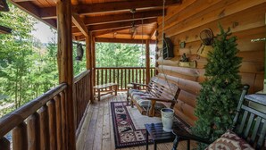 A wooden cabin porch with a bench, a hanging bird feeder, and a small Christmas tree. - Liam's Retreat - 2 Bedroom with GameRoom just minutes away from Pigeon Forge 2 Cabin by RedAwning (Sevierville)
