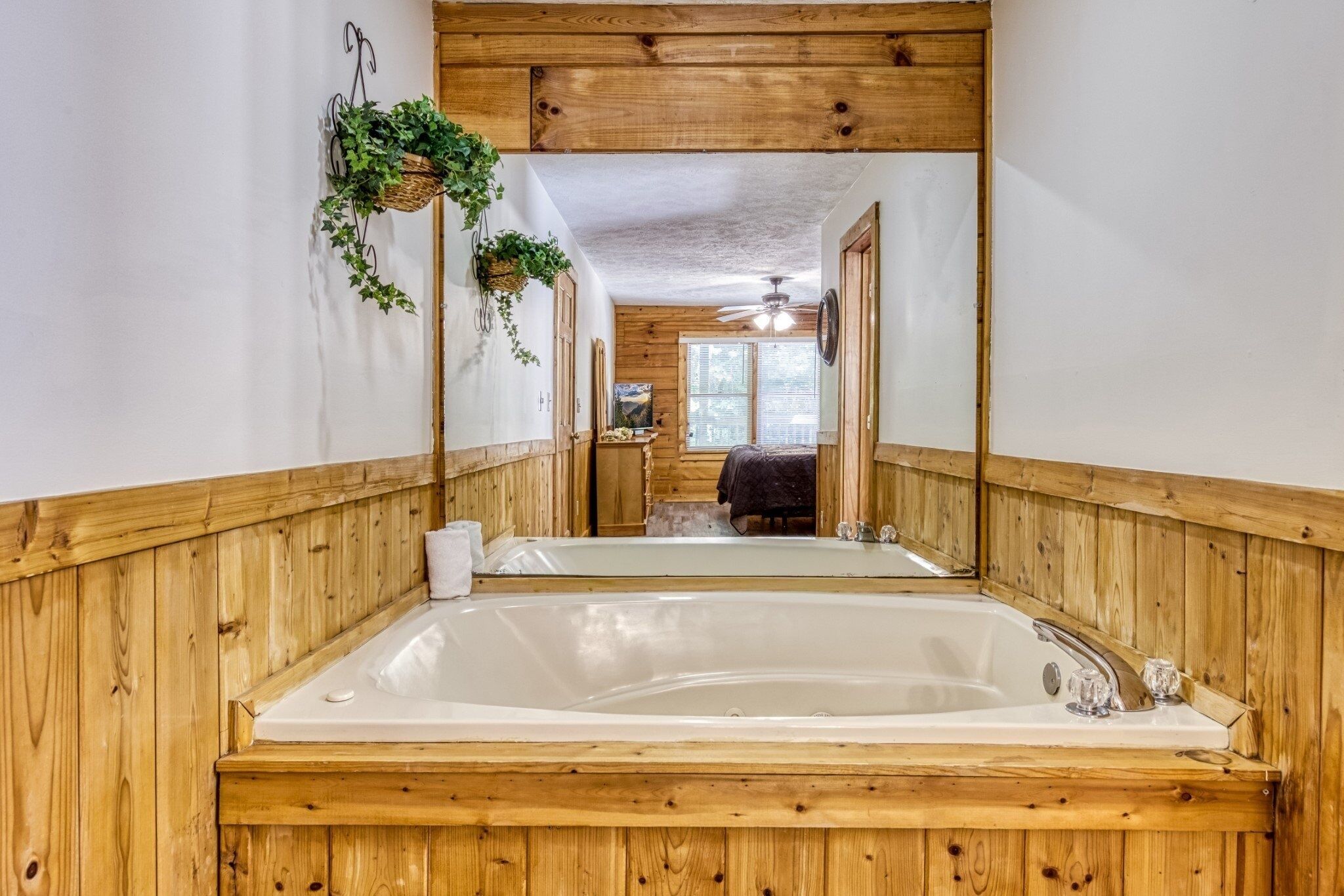 Un baño con paneles de madera, un espejo grande, una bañera y un ventilador de techo.