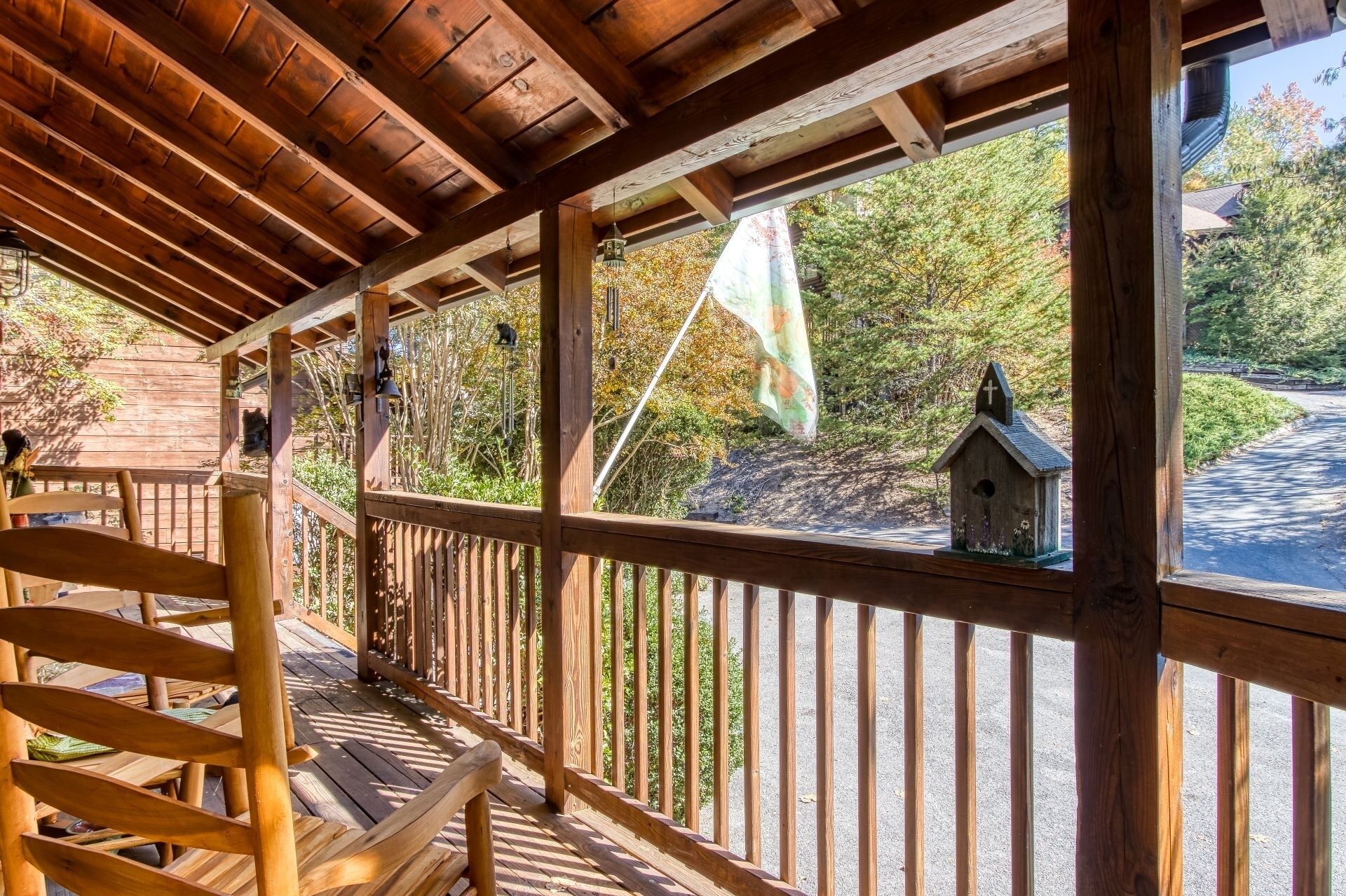 A wooden deck with a railing, a wooden bench, and a birdhouse.