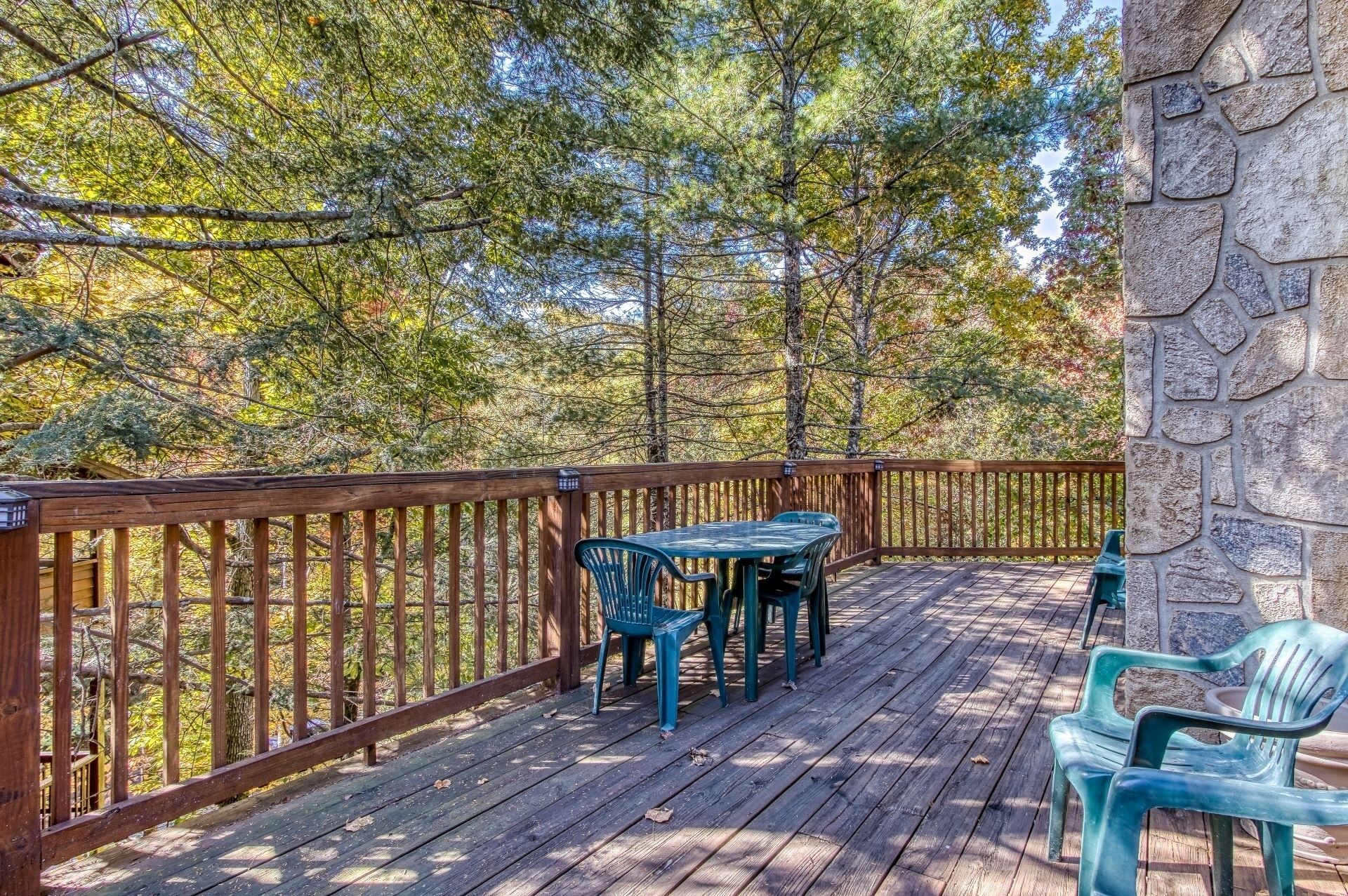 A wooden deck with a stone wall, surrounded by trees.