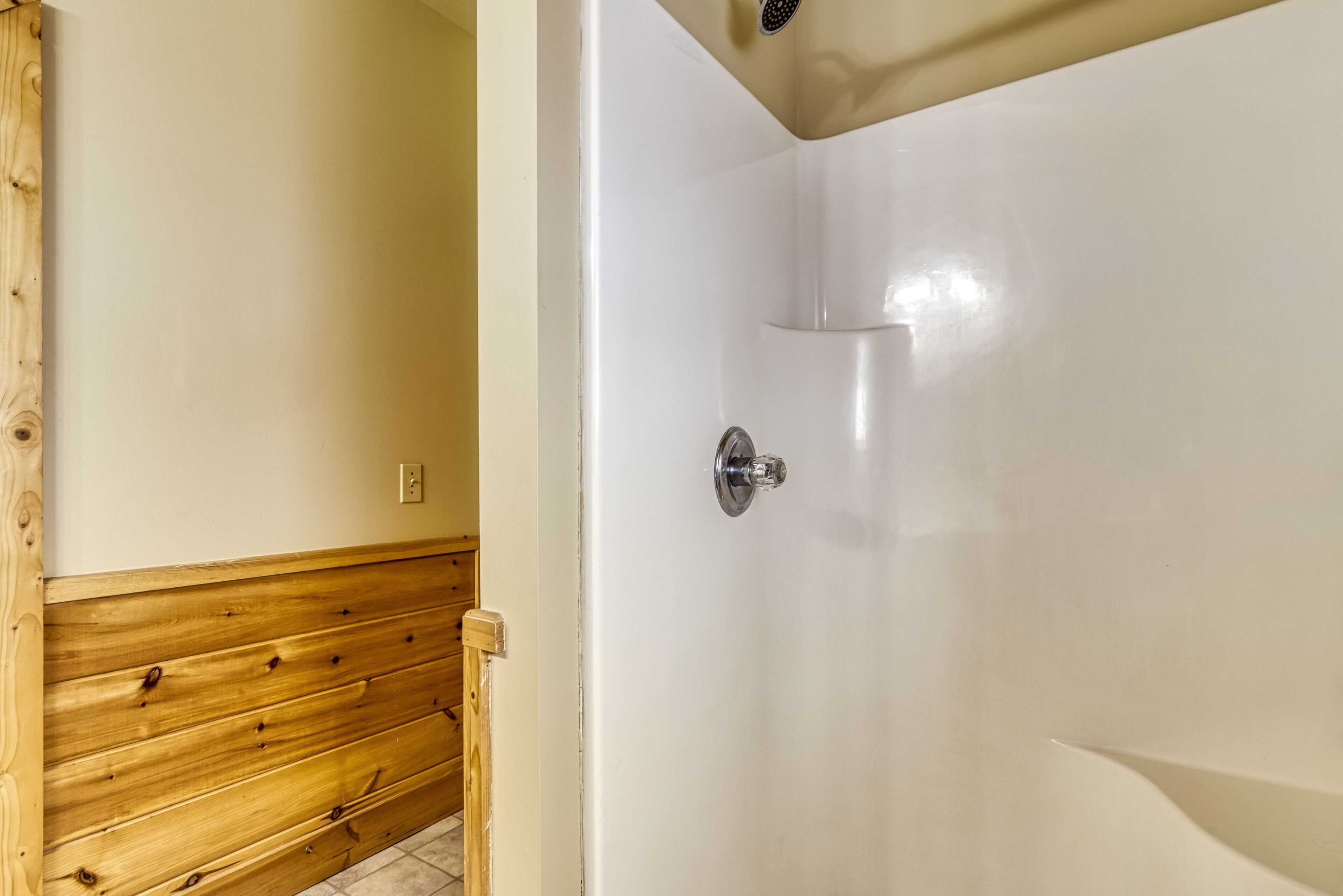 Un mur en bois, juste à côté d’une porte blanche dotée d’une poignée argentée.