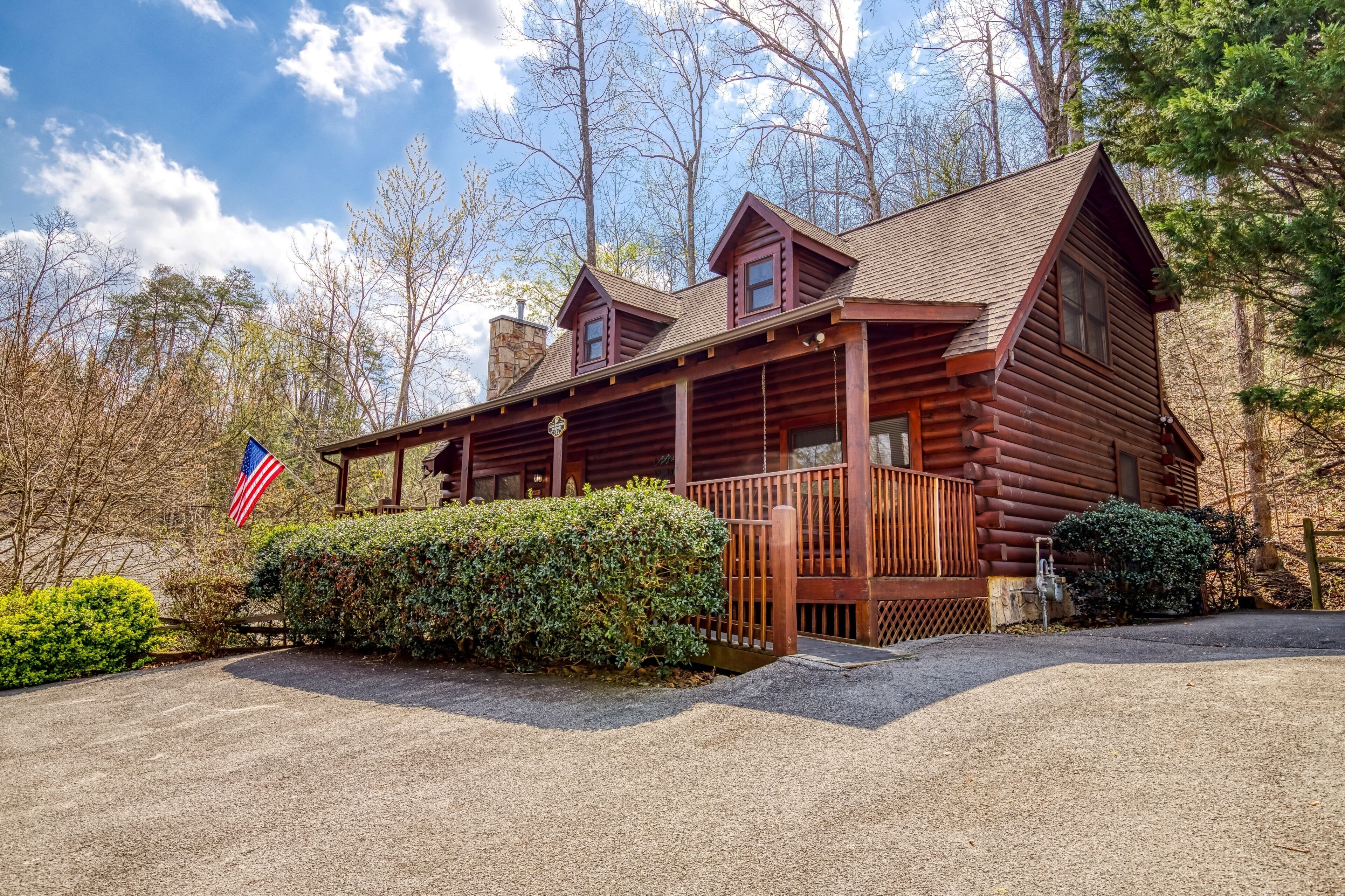 A log cabin with a porch, a flag, and a well-maintained garden.