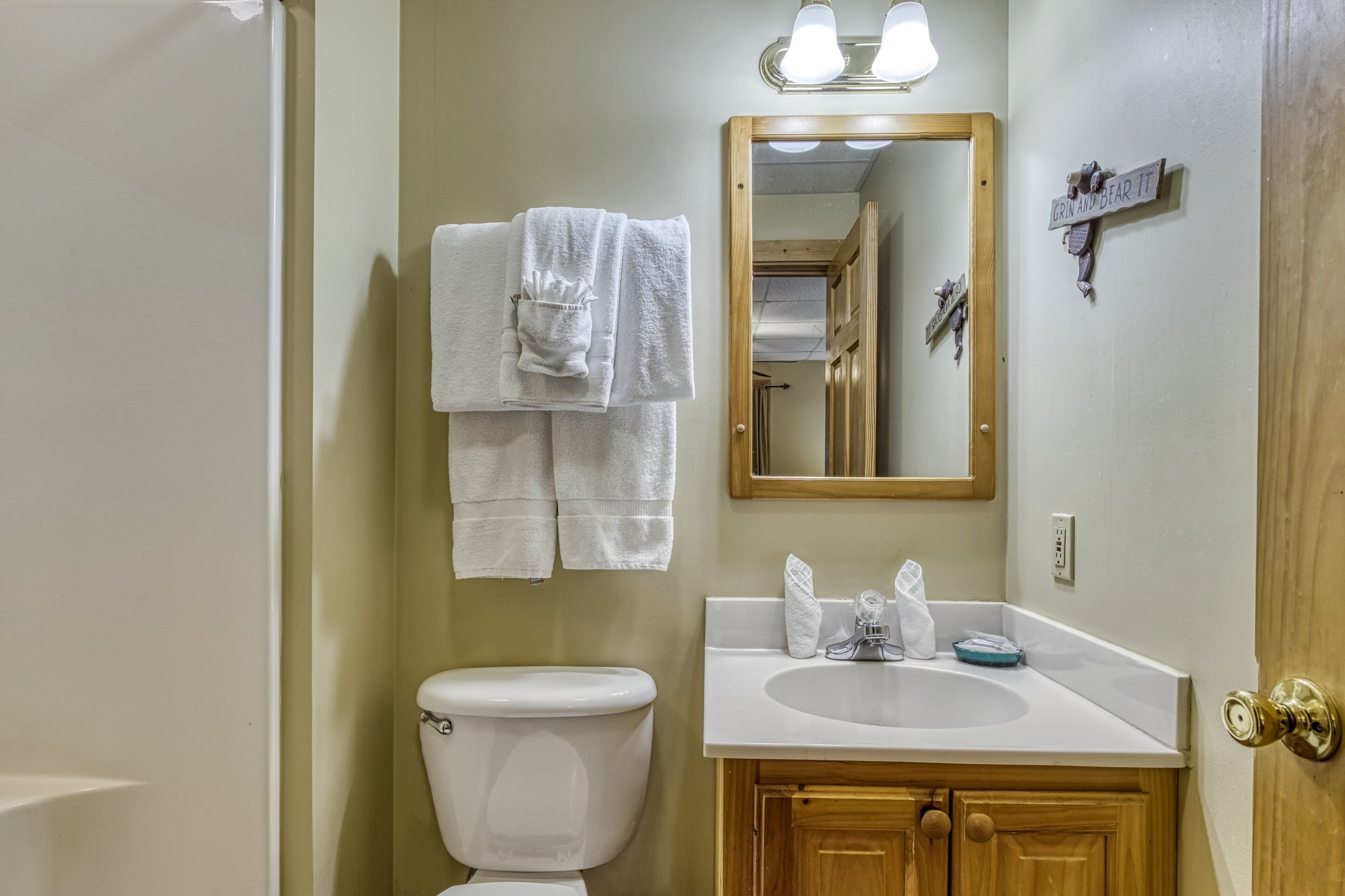A bathroom with a toilet, sink, mirror, and towels.