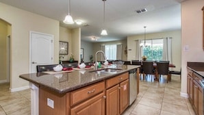 A spacious kitchen with granite countertops, wooden cabinets, and a central island. - Paradise Palms-6 bedrooms House w-pool-3509PP 6 Home by RedAwning (Kissimmee)