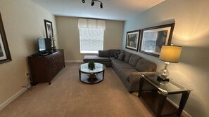 A living room with a sofa, a coffee table, a TV on a stand, a lamp, and framed pictures on the wall. - Paradise Palms-6 bedrooms House w-pool-3509PP 6 Home by RedAwning (Kissimmee)