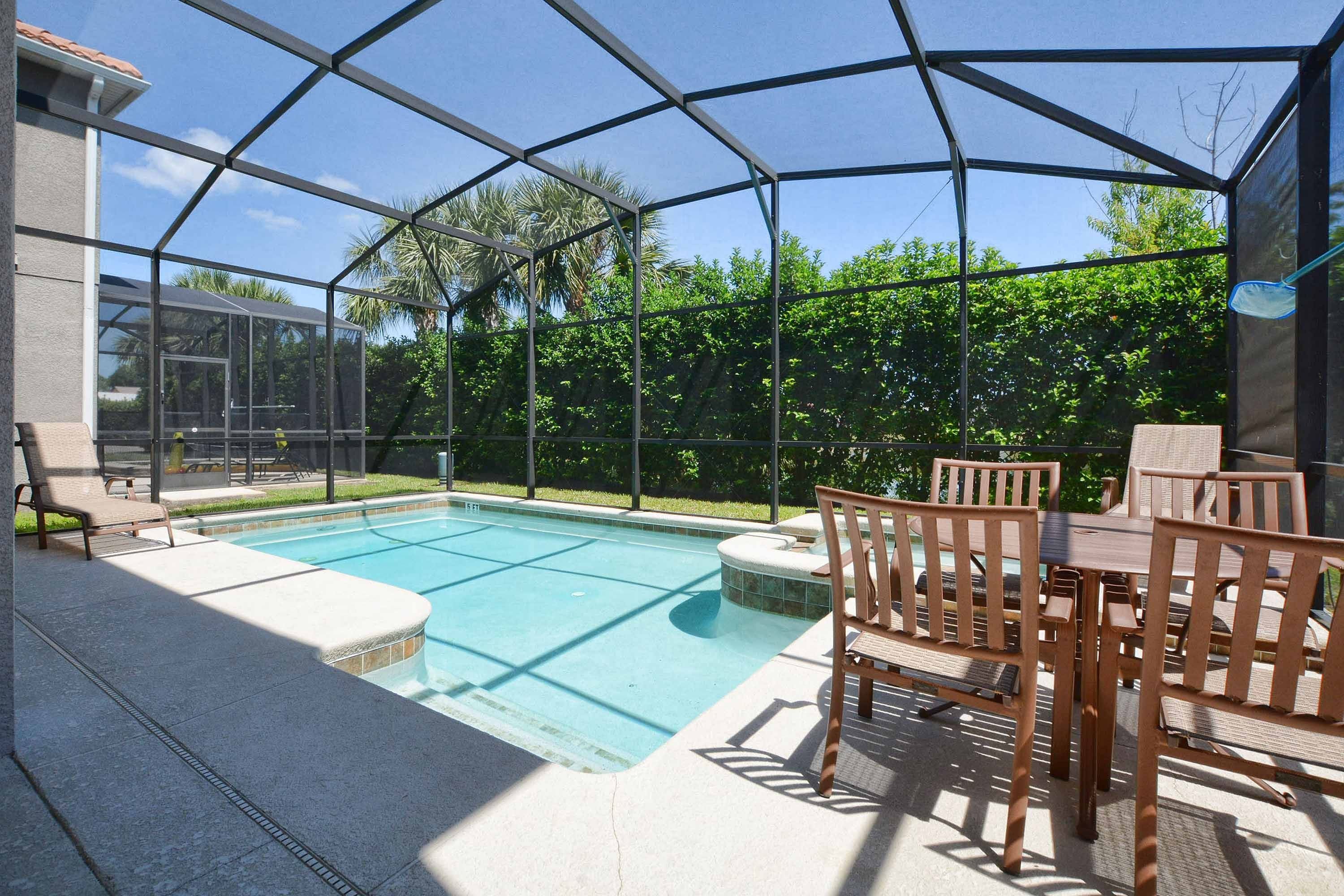 Une piscine extérieure couverte avec un espace patio comprenant une table et des chaises.