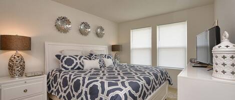 A bedroom with a bed, bedside tables, wall art, and a television.