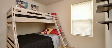 A bunk bed with a ladder, a window with blinds, and a wall with two Mickey Mouse posters.