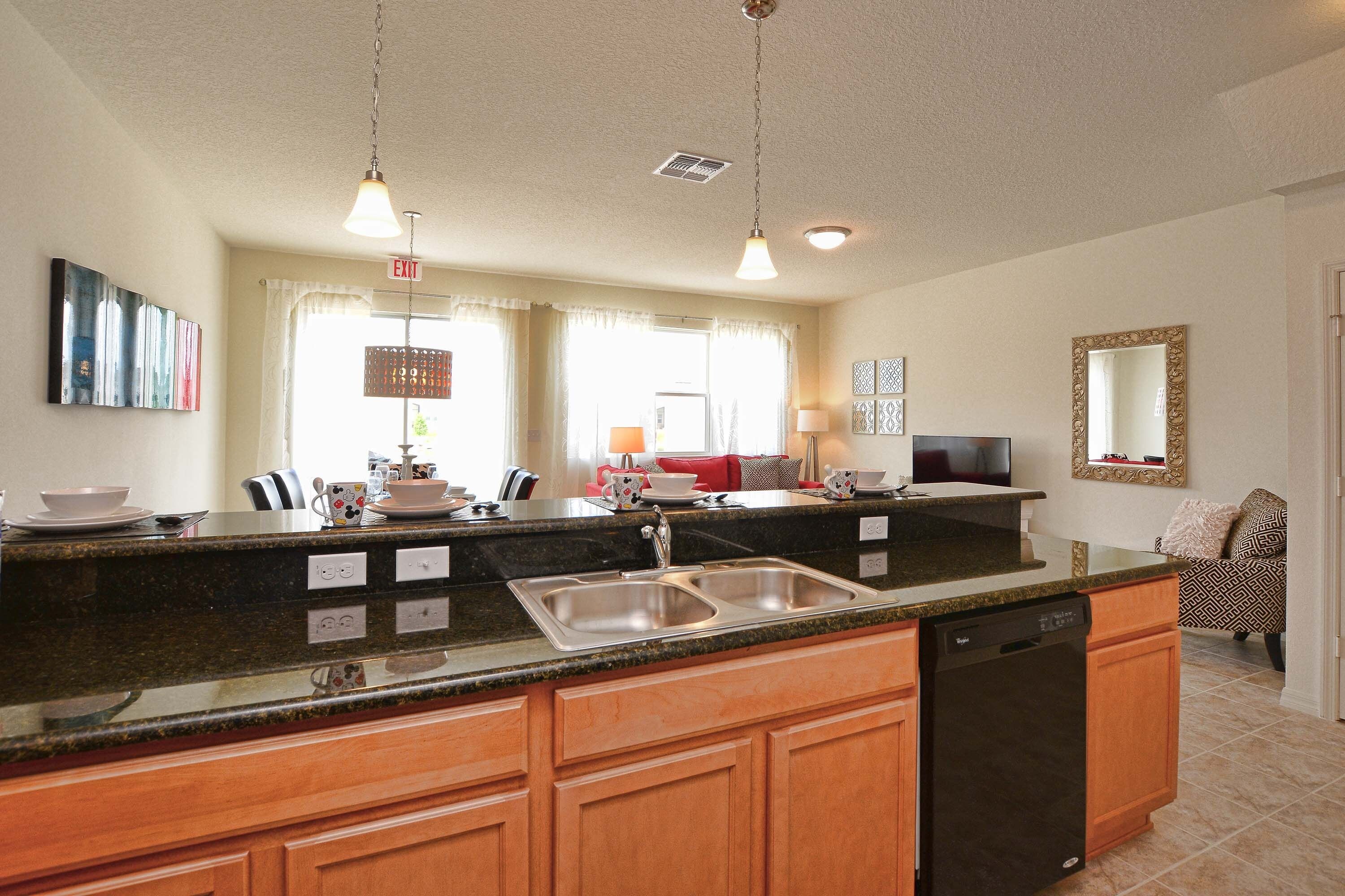 A kitchen with a granite countertop, wooden cabinets, a dishwasher, and a sink.