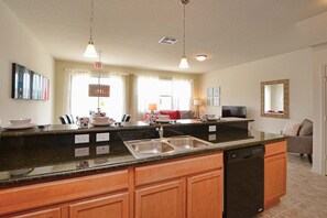 A kitchen with a granite countertop, wooden cabinets, a dishwasher, and a sink.
