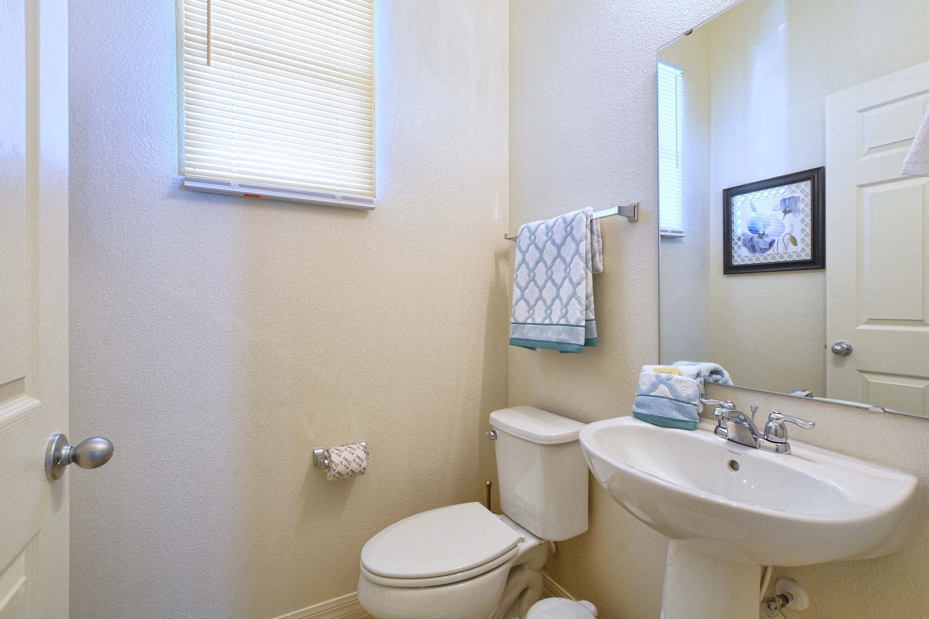 A bathroom with a toilet, sink, and window.