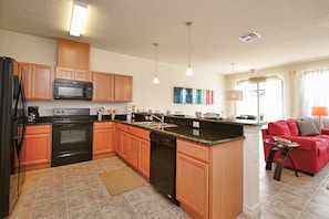 A modern kitchen with wooden cabinets, a built-in microwave, a dishwasher, and a granite countertop. - Compass Bay- 4 Bedroom Townhome - 1954CY 4 Townhouse by RedAwning (Kissimmee)