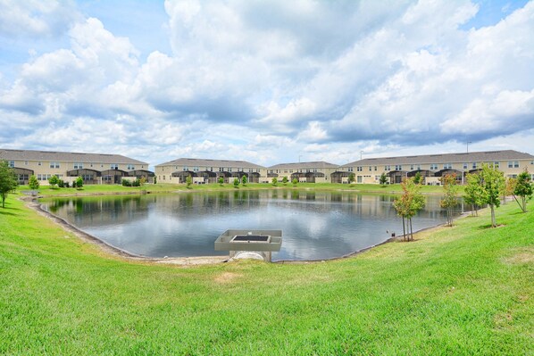 A residential complex with multiple apartment buildings, a central pond, and a grassy area.